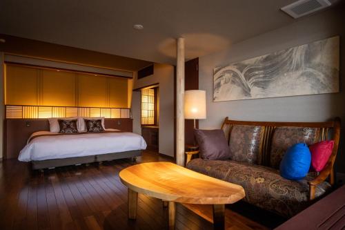 a bedroom with a bed and a couch and a table at Isaribi (No Children) in Higashiizu