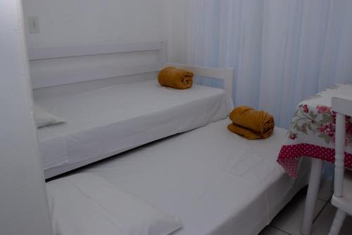 Duas camas brancas num pequeno quarto com toalhas amarelas em Residencial Neto em Florianópolis