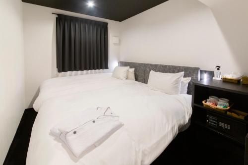 a bedroom with a white bed with a bag on it at HOTEL TRAD Replay in Osaka