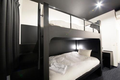 a bedroom with two bunk beds with white sheets at HOTEL TRAD Replay in Osaka