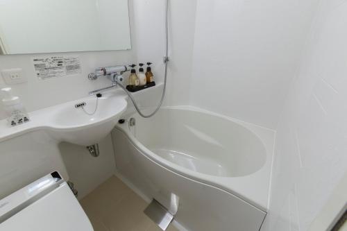a white bathroom with a sink and a bath tub at HOTEL TRAD Replay in Osaka