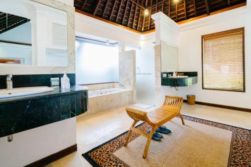 bagno con lavandino, vasca e sedia di Avillion Villa Cinta @Sanur, Bali a Sanur