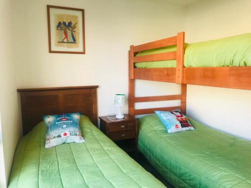 2 literas en una habitación con sábanas verdes en Cosmopolita Verde, en La Serena