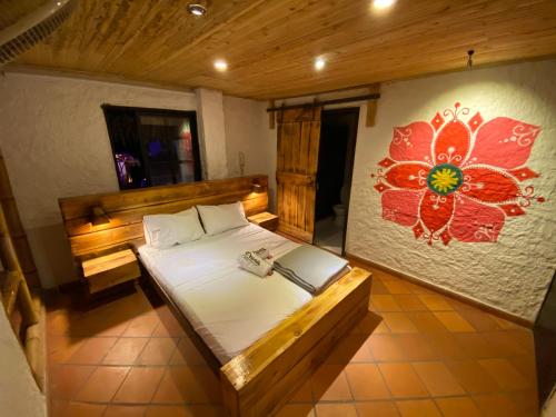 een slaapkamer met een bed met een bloem aan de muur bij Prana in San Gil