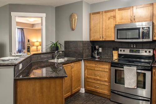a kitchen with stainless steel appliances and wooden cabinets at Modern Cozy 2 Bed 2 Bath with Lake and Mountain Views Pool and Hot Tub in Invermere