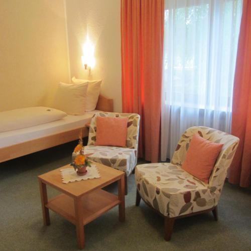 a room with a bed and two chairs and a table at Hotel Angermeier GARNI in Eching