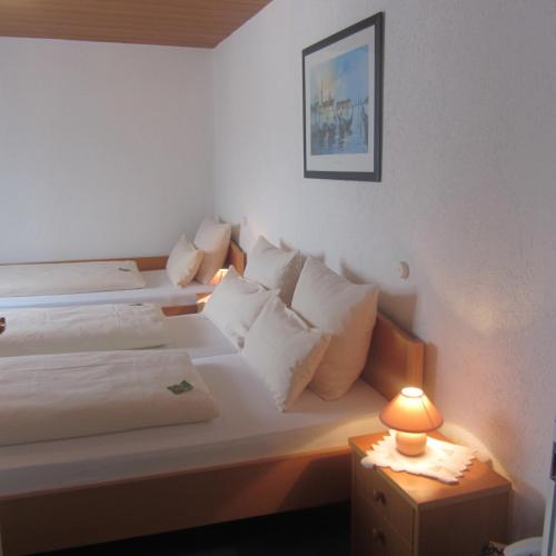 two beds in a room with a lamp on a table at Hotel Angermeier GARNI in Eching