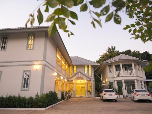 a house with yellow doors and cars parked in the driveway at Promporn Boutique Hotel in Nan