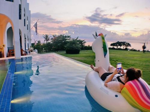 two people riding in an inflatable shark boat in a pool at 地中海海景包棟-無邊際泳池 家庭出遊 朋友聚會 生態體驗 推薦包棟首選 in Xiaoliuqiu