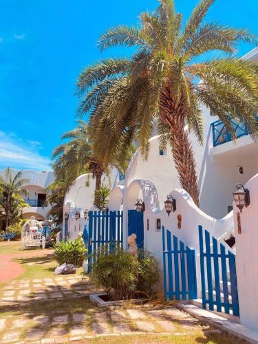 a palm tree next to a white building with a blue fence at 地中海海景包棟-無邊際泳池 家庭出遊 朋友聚會 生態體驗 推薦包棟首選 in Xiaoliuqiu