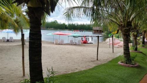 a beach with chairs and umbrellas on the sand at Tara Beach Resort Udonthani in Udon Thani