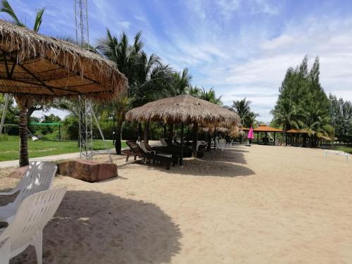 a beach with chairs and straw umbrellas on the sand at Tara Beach Resort Udonthani in Udon Thani