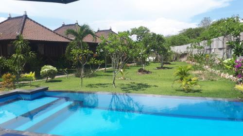 a swimming pool in front of a house with a yard at Gatri Hut in Nusa Lembongan