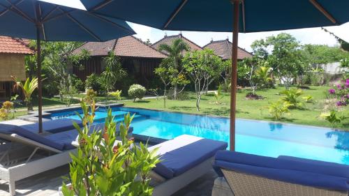 a pool with chairs and umbrellas next to a resort at Gatri Hut in Nusa Lembongan