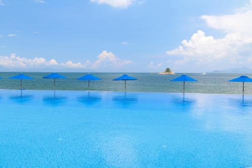 a group of blue umbrellas on a beach with the ocean at Intercontinental Shenzhen Dameisha Resort by IHG in Shenzhen