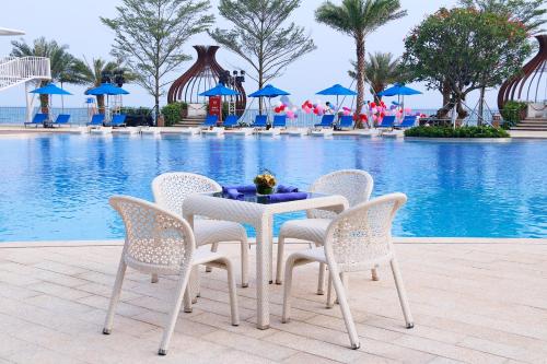 a table and chairs in front of a swimming pool at Intercontinental Shenzhen Dameisha Resort by IHG in Shenzhen