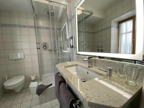 a bathroom with a sink and a toilet and a mirror at Hotel Lobmeyer in Roding