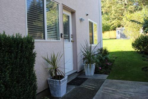a house with two potted plants next to a door at Memory Lane Guest Suite in Sooke