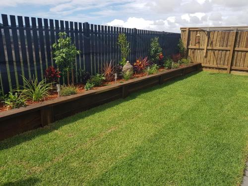 a fence with a row of plants in a yard at Hampton Homestay in Palmview