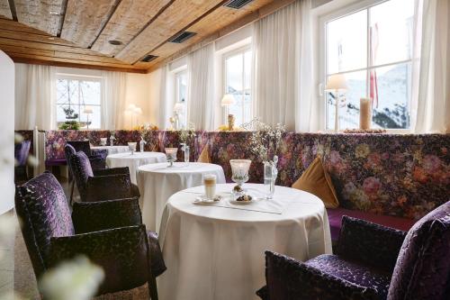 un restaurante con mesas y sillas blancas y ventanas en Alpenhotel St.Christoph, en Sankt Christoph am Arlberg