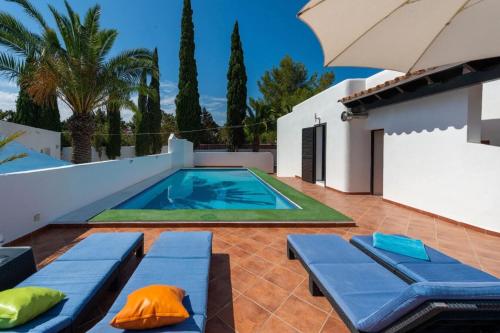 ein Pool mit zwei blauen Bänken und einem Sonnenschirm in der Unterkunft Villa Ca Daniela in Sant Antoni de Portmany