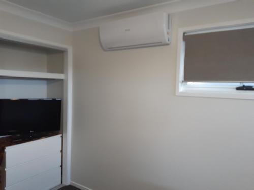 a living room with a tv and a window at Hampton Homestay in Palmview