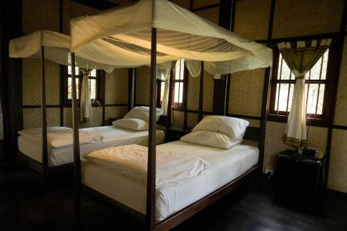 two twin beds in a room with windows at Nong Kiau Riverside in Nongkhiaw