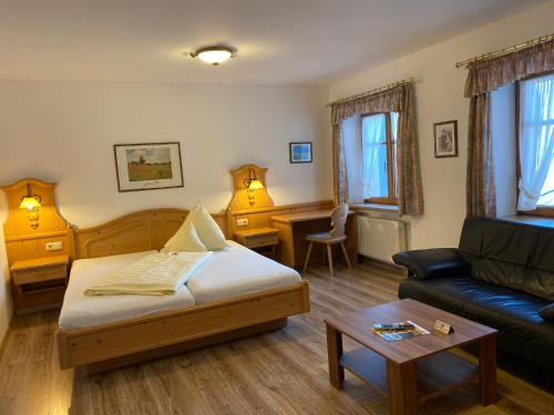 ein Wohnzimmer mit einem Bett und einem Sofa in der Unterkunft Hotel Lobmeyer in Roding