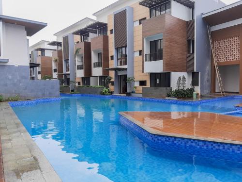 a swimming pool in front of some apartment buildings at Convenient and Luxurious 2BR Asatti Apartment By Travelio in Pagedangan