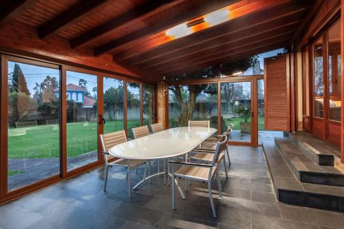 a dining room with a table and chairs on a patio at Oktheway Villa Maneiro in Bergondo