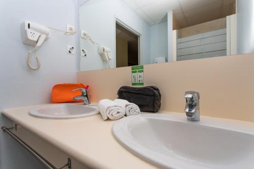 a bathroom with a sink and a mirror at Hotel The Originals Tours Sud Pic Epeiche (ex Inter-Hotel) in Montbazon