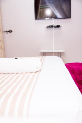 a bedroom with a white bed with a tv on the wall at Villa Prince in Harare