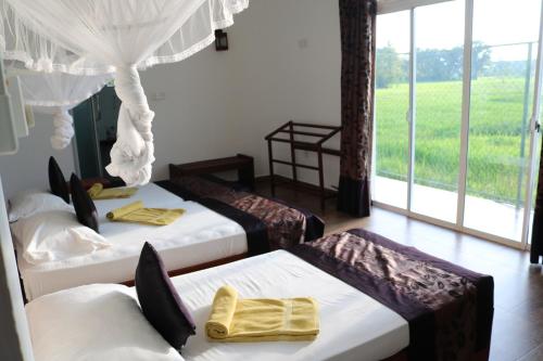 three beds in a room with a view at Manel Guest House in Polonnaruwa