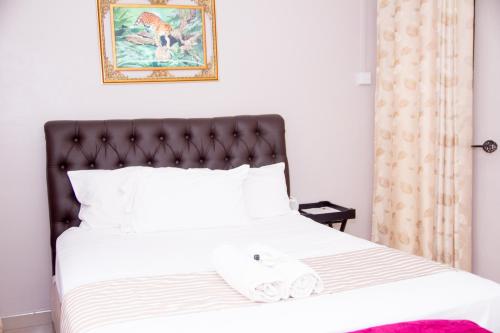 a bedroom with a white bed with a black headboard at Villa Prince in Harare