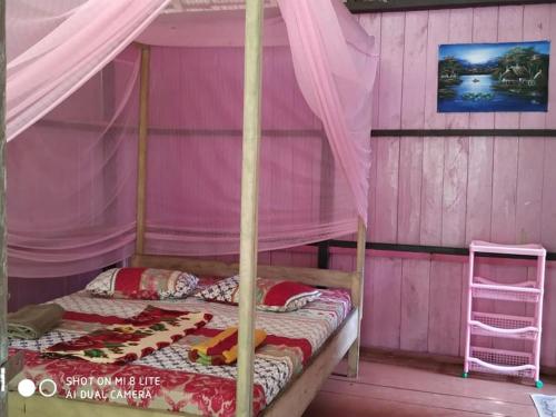 Habitación de color rosa con cama con dosel. en Sunset Beach en Batudaka