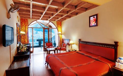 a bedroom with a red bed and a living room at Shingar Regency in Manāli