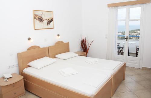 a bedroom with a bed with white sheets and a window at Aiolos Iraklia in Iraklia