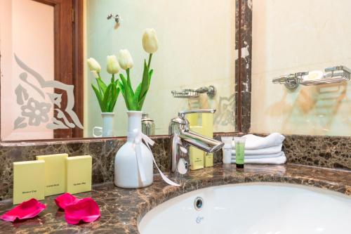 a bathroom sink with a white tub and flowers at Al Diyafa Furnished Suites in Doha