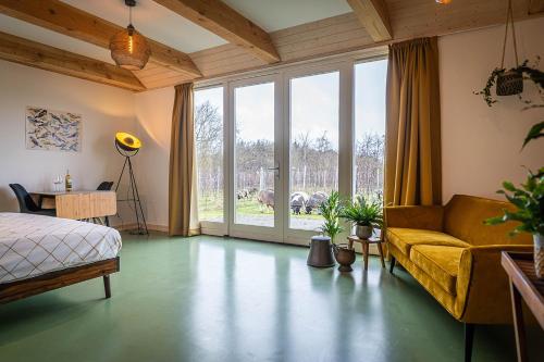 een slaapkamer met een bed, een bank en een raam bij Wijngaard de Kroon van Texel in Den Burg