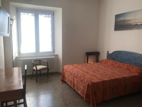 um quarto com uma cama, uma mesa e uma janela em Domus Zoe em Forte dei Marmi