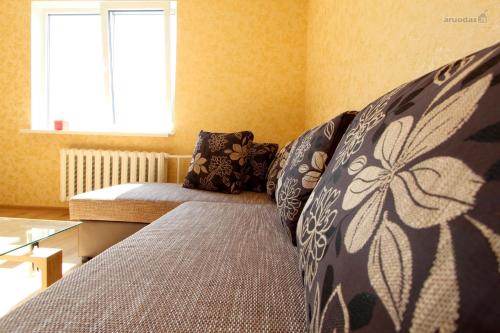 een bed in een kamer met een raam en kussens bij Lukšio Apartment in Šiauliai