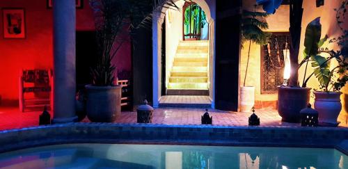 a swimming pool in front of a building with stairs at Riad Mehdia in Marrakech