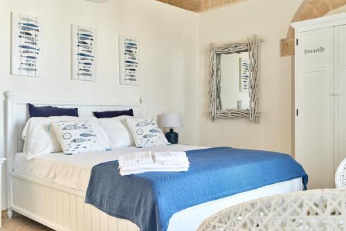 a bedroom with a bed with a blue blanket and a mirror at POSEA - Polignano Sea Suites in Polignano a Mare