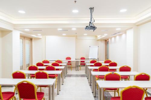 a room with white tables and red chairs at Olympus Terra Boutique Hotel in Larisa