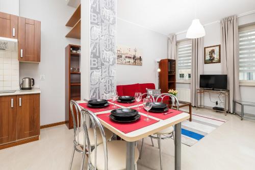 a kitchen and living room with a red table and chairs at Apartments Old Town Ogarna 107 by Renters in Gdańsk
