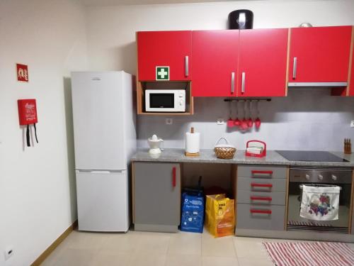 kuchnia z czerwonymi szafkami i białą lodówką w obiekcie Cantinho do Diogo w mieście Calhetas