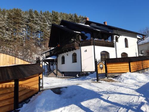 a house in the snow with a fence at CASA DINTRE PINI in Păltinoasa