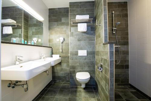 een badkamer met een wastafel, een toilet en een douche bij Bastion Hotel Apeldoorn Het Loo in Apeldoorn