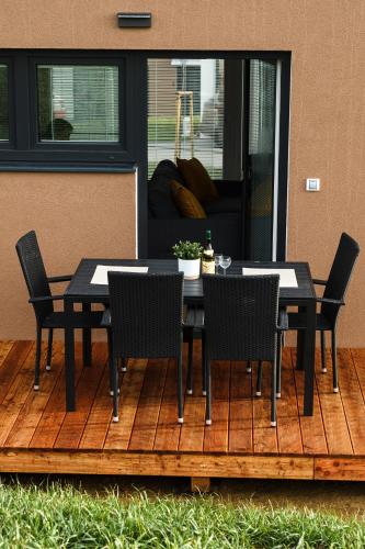 a table and chairs on a deck with a house at Apartmány NMNM REZIDENCE NAD MĚSTEM in Nové Město na Moravě