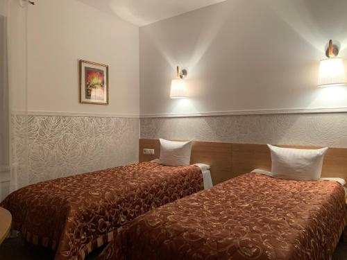 2 Betten in einem Hotelzimmer mit Wandbeleuchtung in der Unterkunft Broliu Vila in Druskininkai